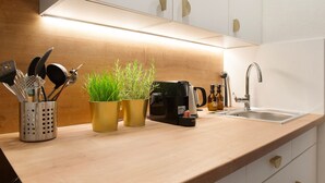A kitchen with a wooden countertop, a coffee maker, a sink, and potted plants.