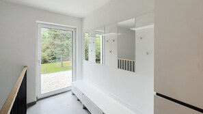 Une salle de bain moderne dotée d’un grand miroir, d’une douche et offrant une vue sur un espace extérieur verdoyant.