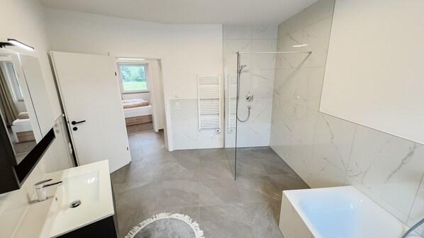 Une salle de bain moderne équipée d’une douche, d’une baignoire et d’un lavabo.