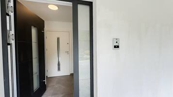 Een modern interieur met een schuifdeur, een deur met een handgreep en een intercom bevestigd aan de muur.