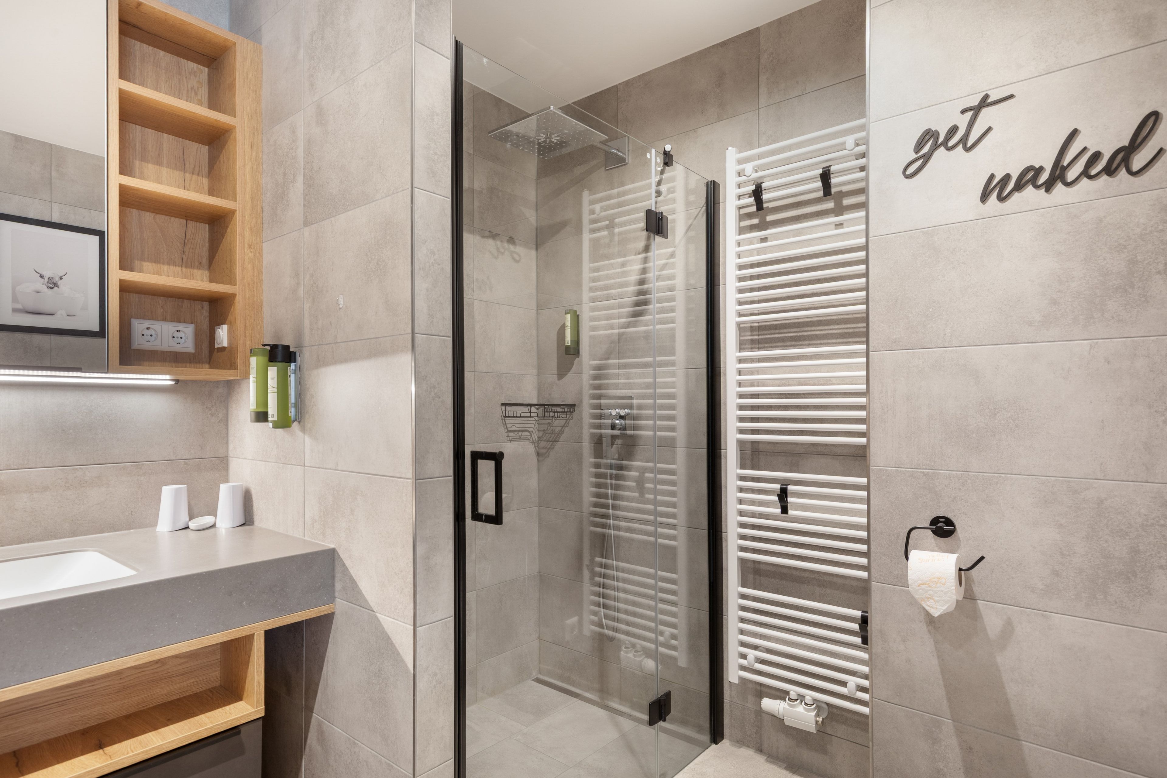 Ein modernes Badezimmer mit einer Duschkabine aus Glas, einem Handtuchhalter und einem Ablagefach für Toilettenartikel.