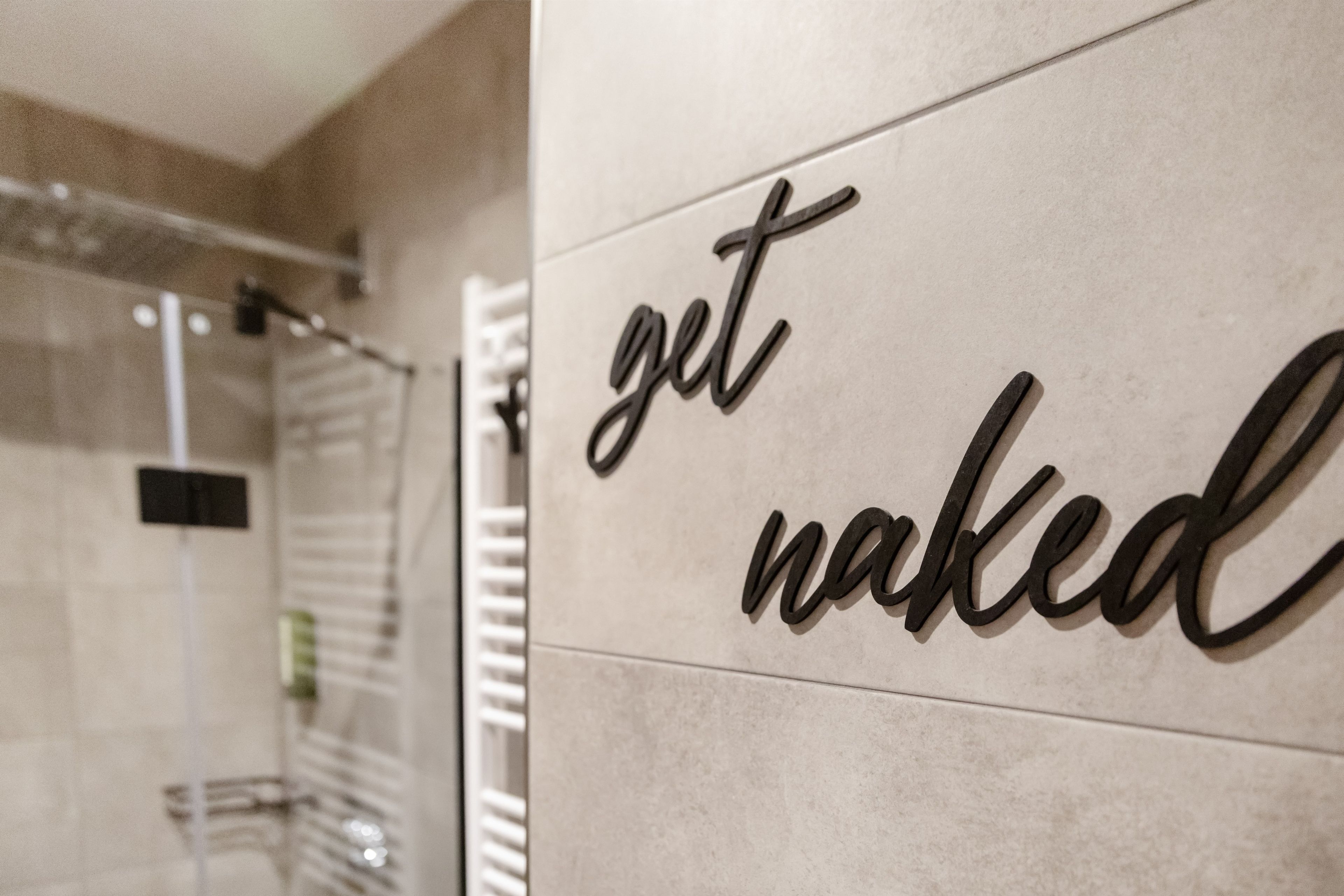 Un bagno con un cartello appeso al muro che recita 'get naked'.