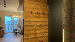 Een modern interieur met een houten wand, een rode stoel en een glazen scheidingswand.