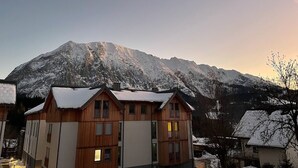 Een houten chalet met een berg op de achtergrond, met een met sneeuw bedekte dak en een heldere lucht.