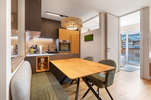 A modern kitchen with wooden cabinets, a built-in oven, and a dining area with a wooden table and chairs.