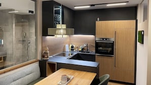 Een moderne keuken met een inbouwoven, een houten kast en een douchecabine van glas.