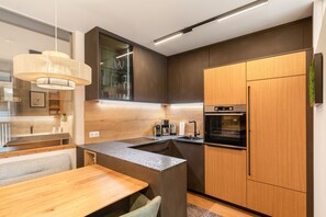 Una cocina moderna con horno empotrado, un armario de madera y una lámpara colgante.