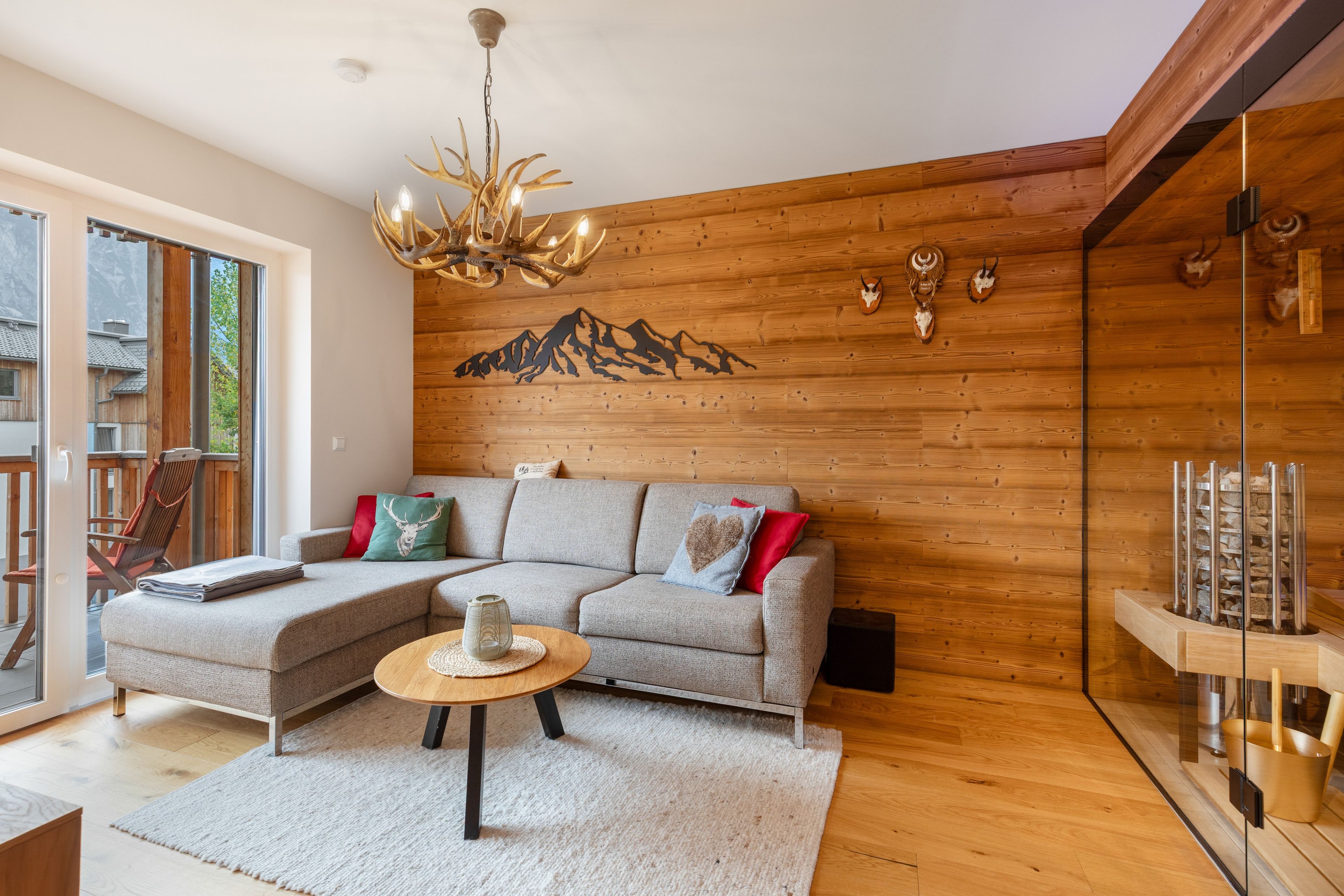 Ein modernes Wohnzimmer mit einer Eckcouch, einer Holzbalkendecke und Wandkunst mit einer Bergsilhouette.