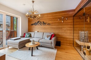 Ein modernes Wohnzimmer mit einer Eckcouch, einer Holzbalkendecke und Wandkunst mit einer Bergsilhouette.