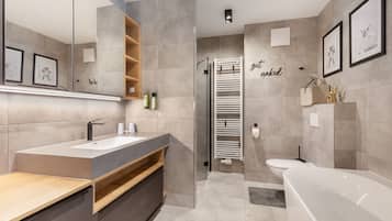 A modern bathroom with a bathtub, a shower, and a vanity with a mirror.