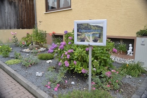 A garden with a sign that reads 'Ferenwohnungoster' and a statue in the background.