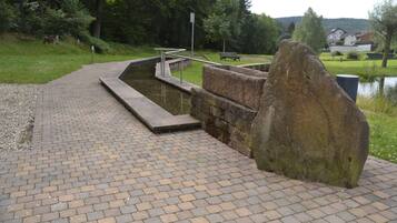 A paved walkway with a stone structure, a metal railing, and a large rock.