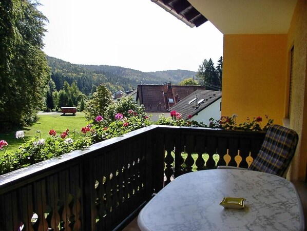 A balcony with a view of a green landscape and a house in the background.