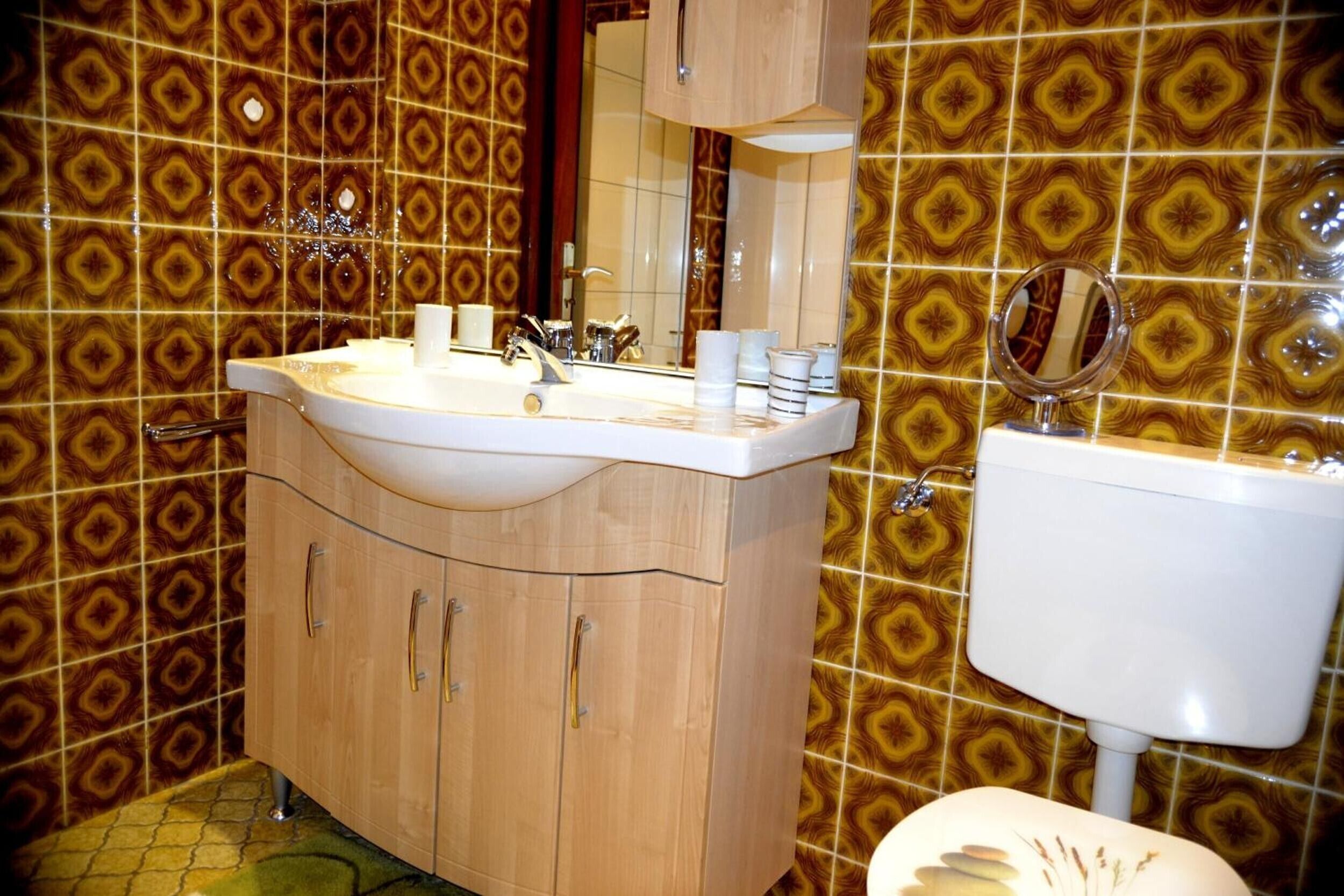 Um banheiro com azulejos estampados, um lavatório de madeira com pia e um espelho.