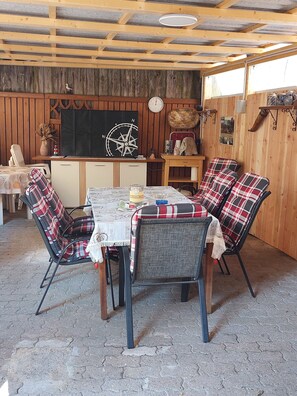 A rustic wooden interior with a round table, plaid chairs, and a compass wall decoration.