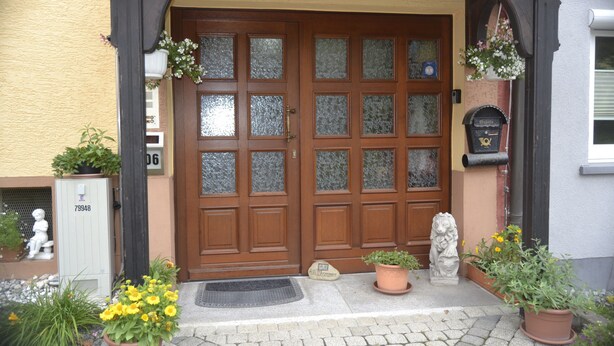 A double wooden door with frosted glass panels, a welcome mat, and potted plants at the entrance. - Apartment 'Haus Moser - Fewo 1' with Valley View, Shared Terrace and Wi-Fi (Eschau)