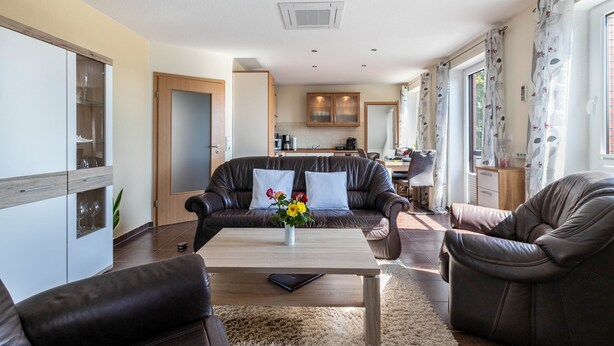 A modern living room with a sofa, coffee table, and a view into the kitchen. - Apartment 'Ferienwohnung  Mühlenweide' with Shared Terrace, Wi-Fi and Air Conditioning (Süderdeich)