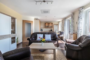 A modern living room with a sofa, coffee table, and a view into the kitchen.