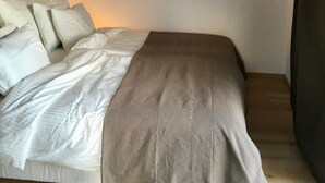 Una camera da letto con un letto, cuscini, una coperta e un lampadario.