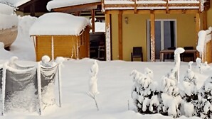 Un rifugio imbiancato dalla neve, con facciata in legno, un balcone e un cortile innevato.