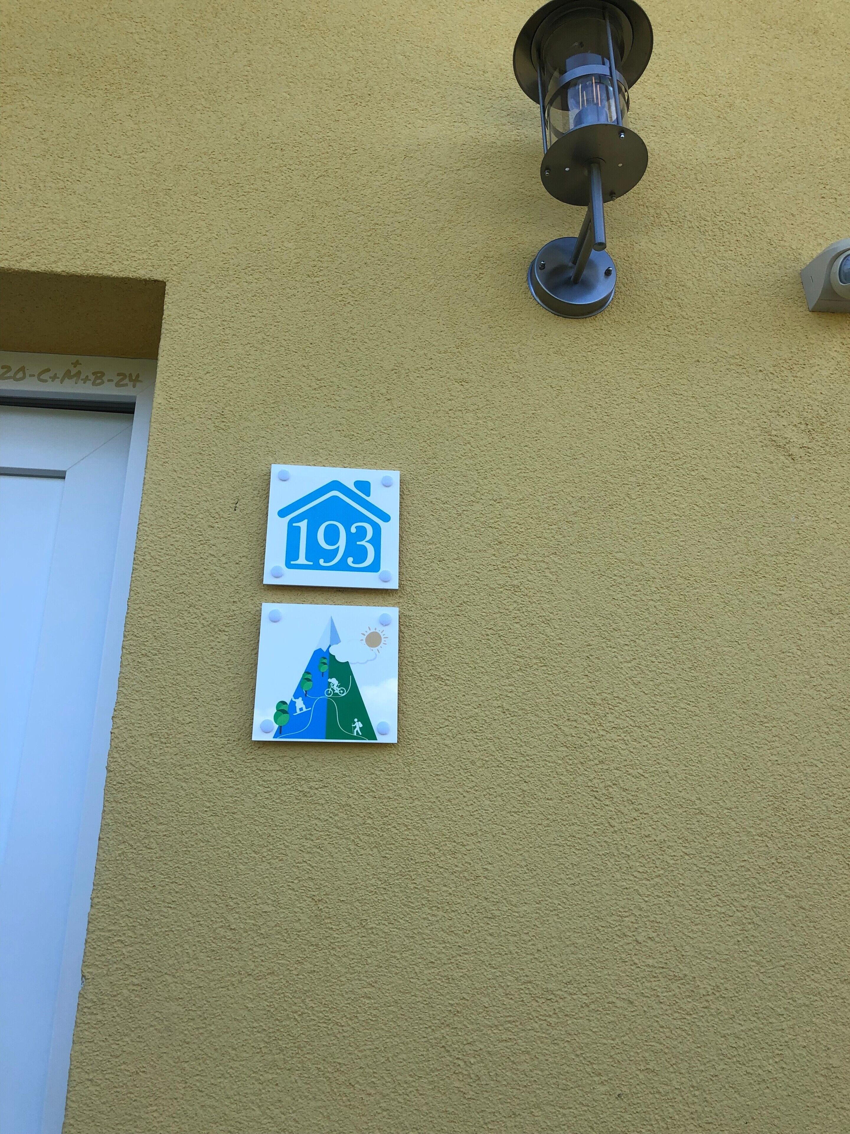 A building with a number sign '193' and a small illustration of a mountain with people and a sun.