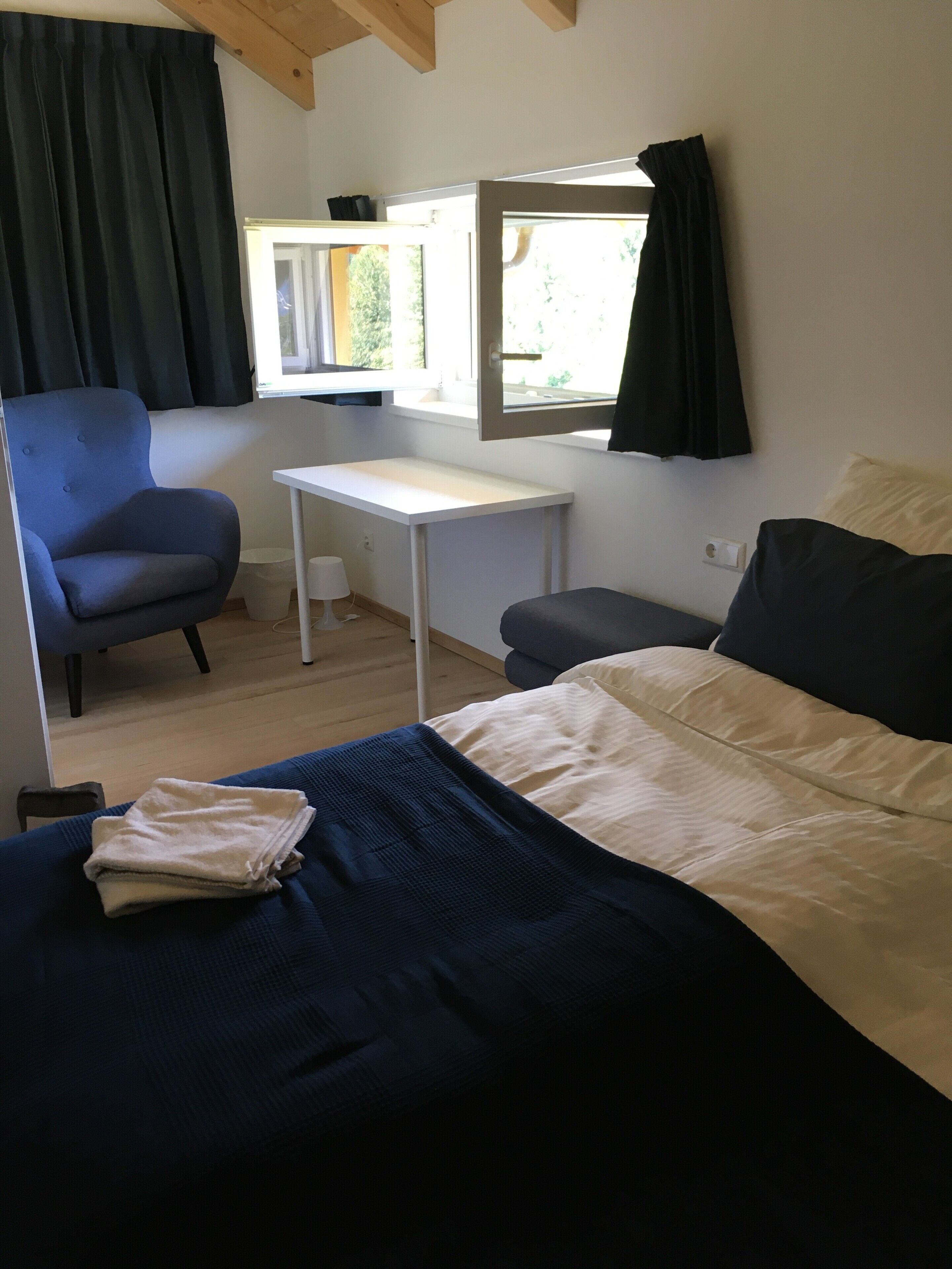 Une pièce comprenant un lit, un bureau, une chaise et une fenêtre.