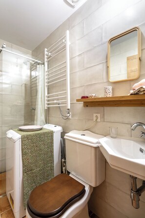 Un baño con inodoro, lavamanos, ducha y espejo.