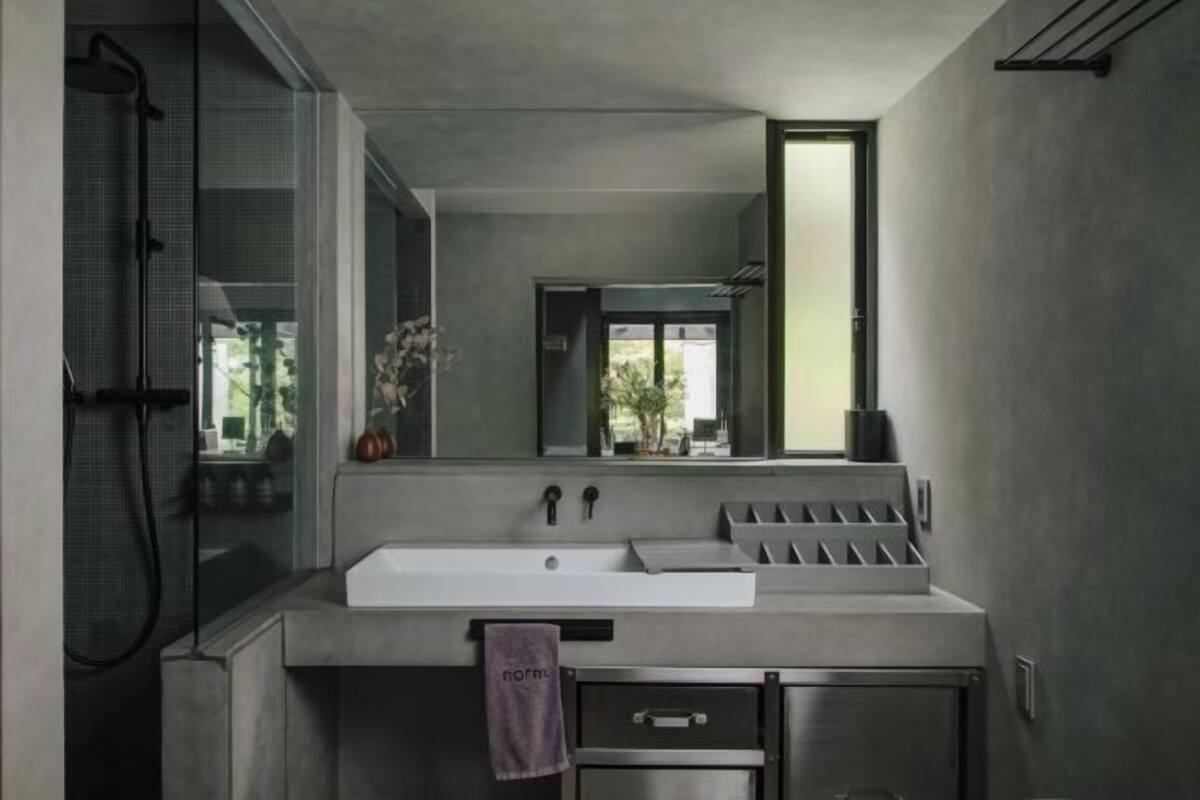 A modern bathroom with a large mirror, a sink, a shower, and a towel rack.
