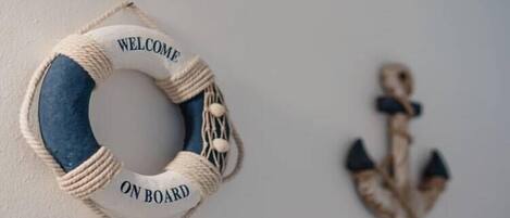 A life preserver with "WELCOME ON BOARD" text and a decorative anchor on a wall.