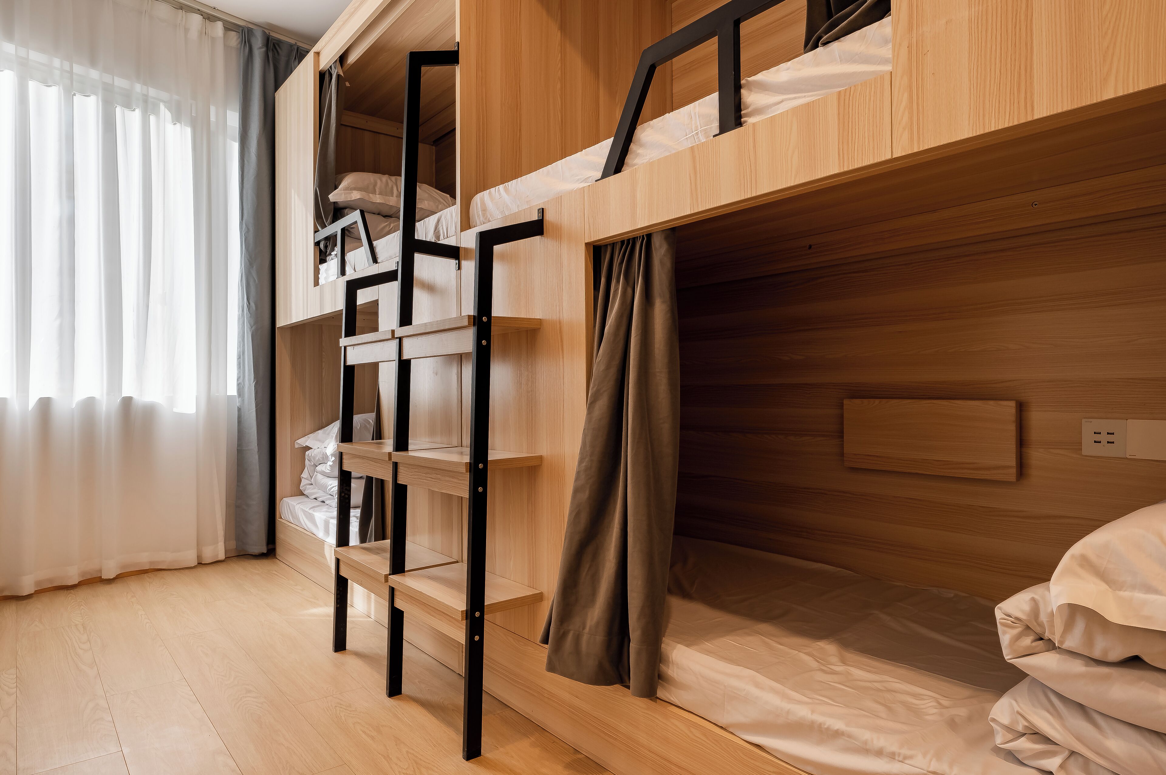 Dormitorio con literas de madera, estante y toma de corriente.