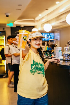 A person holding a beer glass in a bar setting with a counter and shelves in the background. - Dayin International Youth Hostel - People's Square & Old Town (Shanghai)
