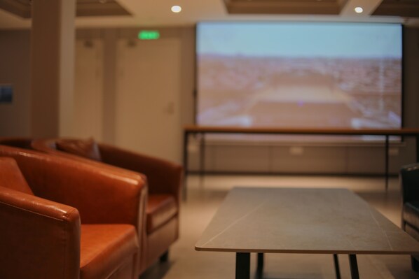 A conference room with a large screen, a table, and leather chairs. - Dayin International Youth Hostel - People's Square & Old Town (Shanghai)