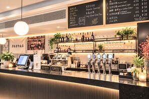 Zona de bar con un menú digital, múltiples grifos de cerveza y una variedad de botellas y vasos.
