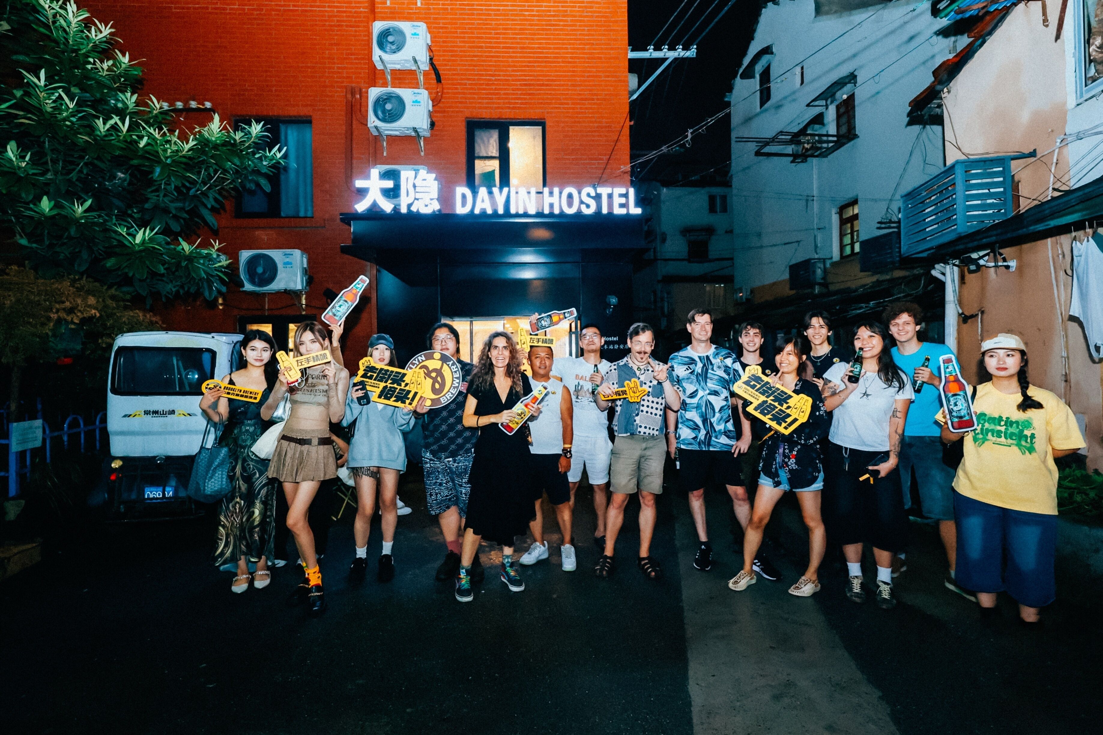 Un grupo de personas frente a un edificio con un letrero que dice "DAYINHOSTEL".