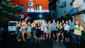 Un grupo de personas frente a un edificio con un letrero que dice "DAYINHOSTEL".