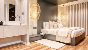 A modern bedroom with a large bed, bedside tables, a mirror, and a hanging light fixture. - Machico Fachos View, a Home in Madeira (Machico)