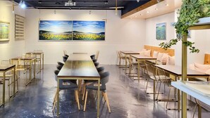 A modern conference room with a long table and chairs, two large paintings on the wall, and a seating area with cushions. - Nampo Hill guesthouse (Busan)