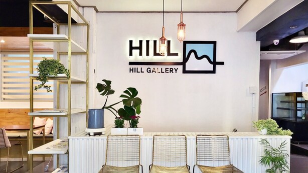 A reception area with a white counter, three gold chairs, a blue potted plant, and a wall-mounted sign reading "HILL GALLERY". - Nampo Hill guesthouse (Busan)
