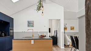 A modern kitchen with a central island, a dining area with chairs, and a white ceiling with a skylight. - "Henke" - 475m from the sea by Interhome (Ålbæk)