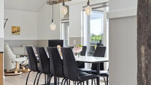 A modern dining area with a white table, black chairs, and a rustic wooden beam ceiling. - "Henke" - 475m from the sea by Interhome (Ålbæk)