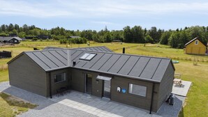 A modern building with a sloped roof, a covered patio area, and a gravel driveway. - "Henke" - 475m from the sea by Interhome (Ålbæk)