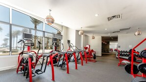 Une salle de sport équipée de tapis de course, de vélos elliptiques et d’un porte-haltères.