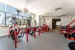 A gym with treadmills, elliptical machines, and a rack of dumbbells.
