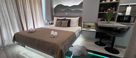 Une chambre d’hôtel moderne dotée d’un grand lit, d’un bureau intégré, d’une coiffeuse et d’une douche en verre.