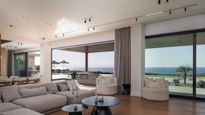 Ein geräumiger Wohnbereich mit einer großen Couch, einem runden Couchtisch und Meerblick.
