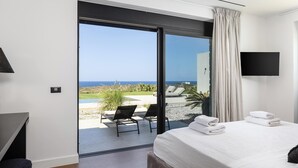 Ein Schlafzimmer mit Bett, Fernseher und Meerblick.