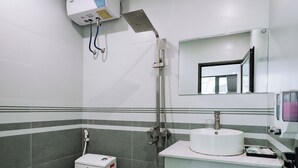 Un baño con inodoro, lavabo, ducha y espejo.