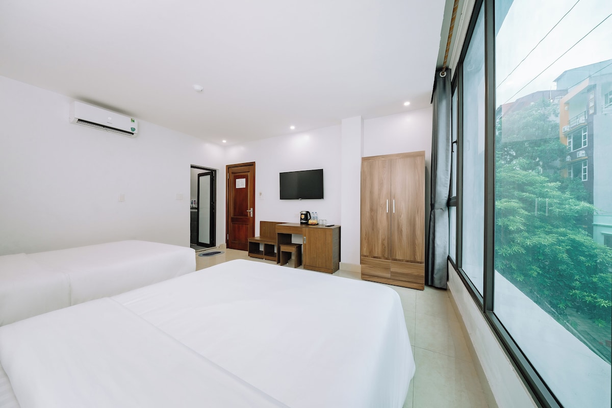 A hotel room with a bed, a desk, a TV, and a wardrobe.