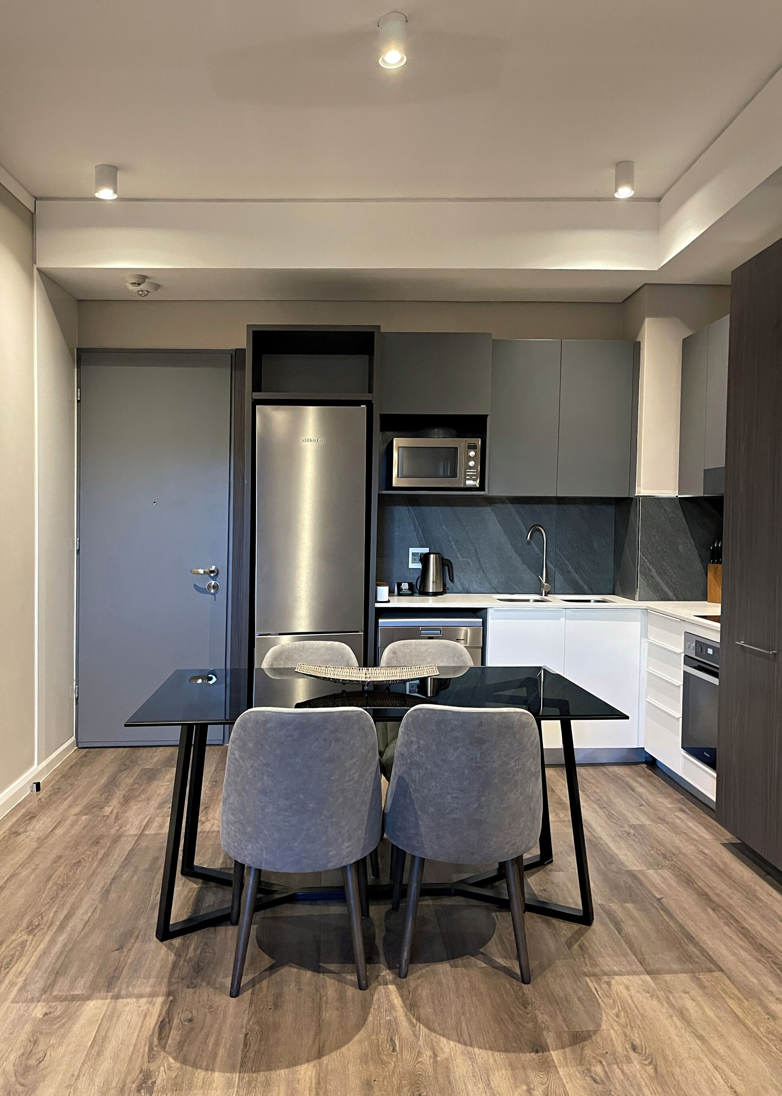 A modern kitchen with a built-in microwave, stainless steel refrigerator, and a coffee maker on the counter.