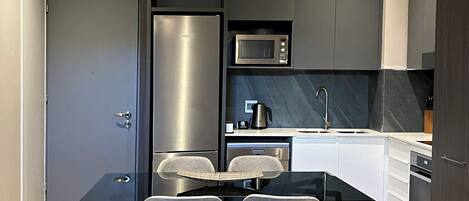 A modern kitchen with a built-in microwave, stainless steel refrigerator, and a coffee maker on the counter.
